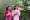 Two Vietnamese women wearing traditional ao dai dresses and both smiling and holding fans