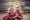 Two Buddhist monks standing in front of a temple and both wearing red robes and have their heads shaved