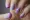 The woman's nails are painted with a light purple polish