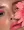 A close-up of a woman's face Also she has pink eyeshadow on her eyes, pink blush on her cheeks, and pink lipstick on her lips