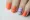 A close-up of a hand with an orange and purple nail polish design