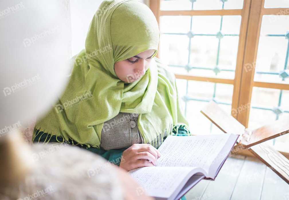 Free Download Premium Stock Photos | Muslim Woman Reading holy Quran very carefully