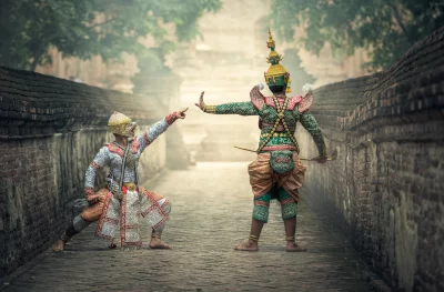 Two Thai dancers actors in traditional costumes performing a Khon dance
